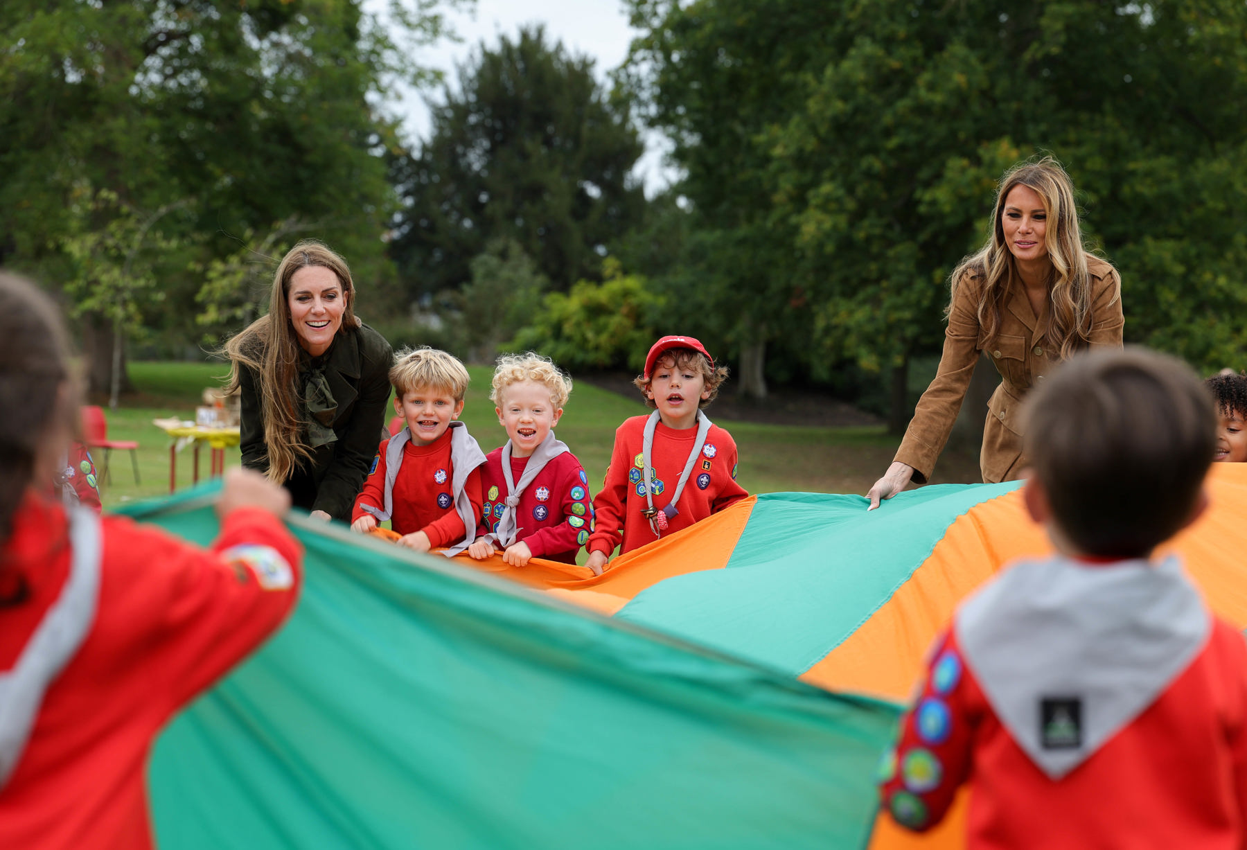 The image shows HRH The Princess of Wales, the First Lady of the United States and 5 Squirrel Scouts holding a parachute.