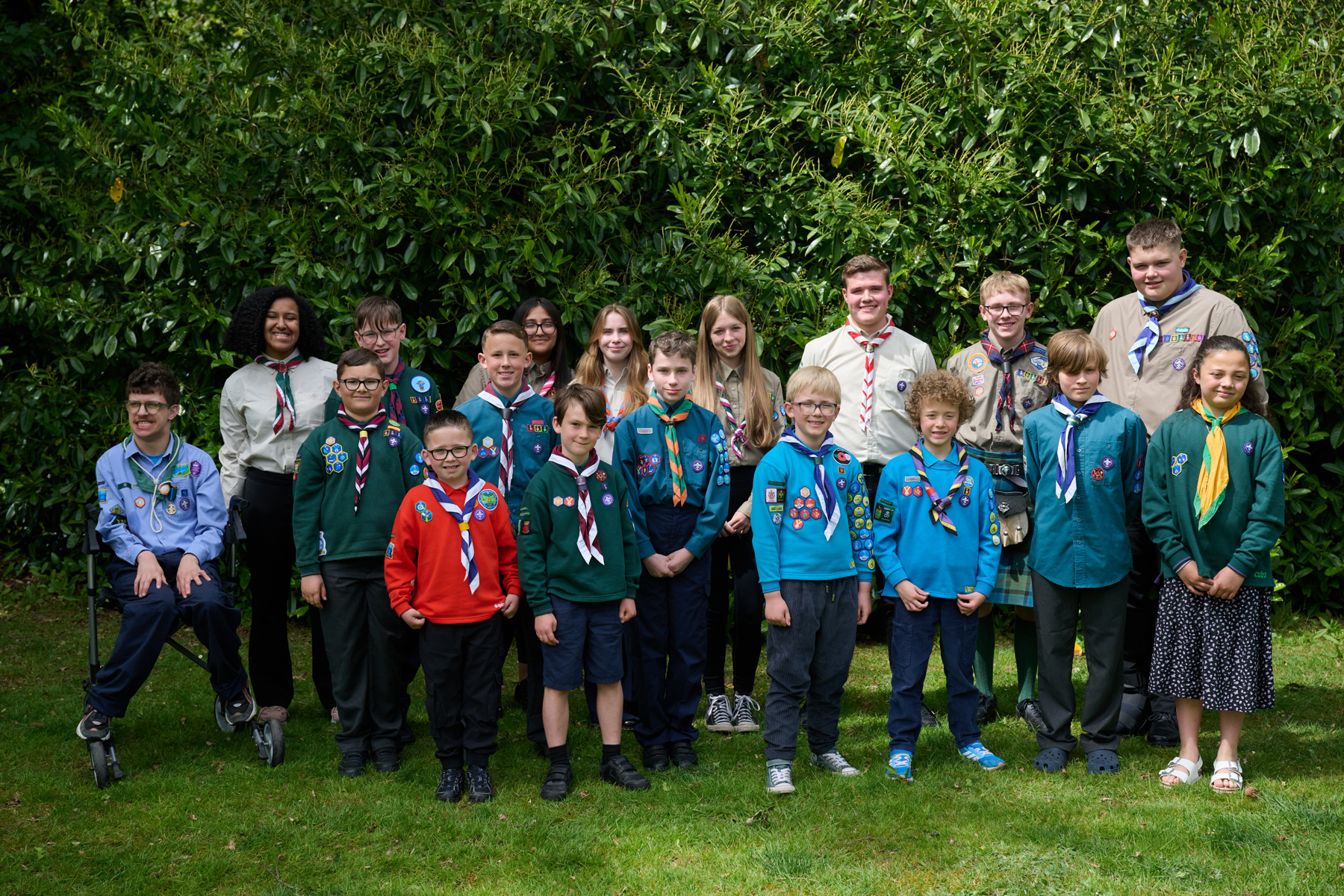 A group of Unsung Heroes, all wearing uniform and standing outside, smile at the camera