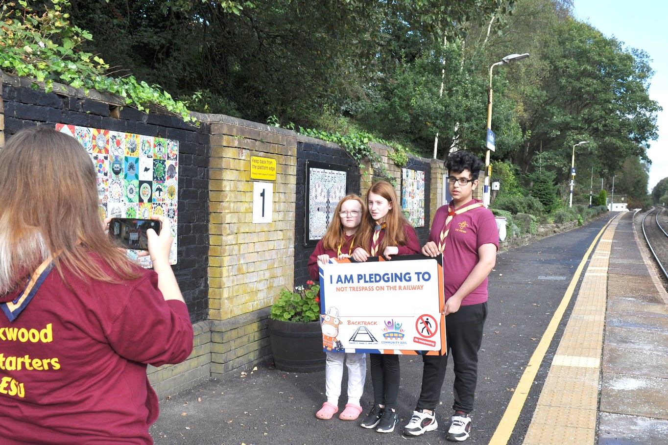 Three Scouts making a Backtrack pledge at a station platform