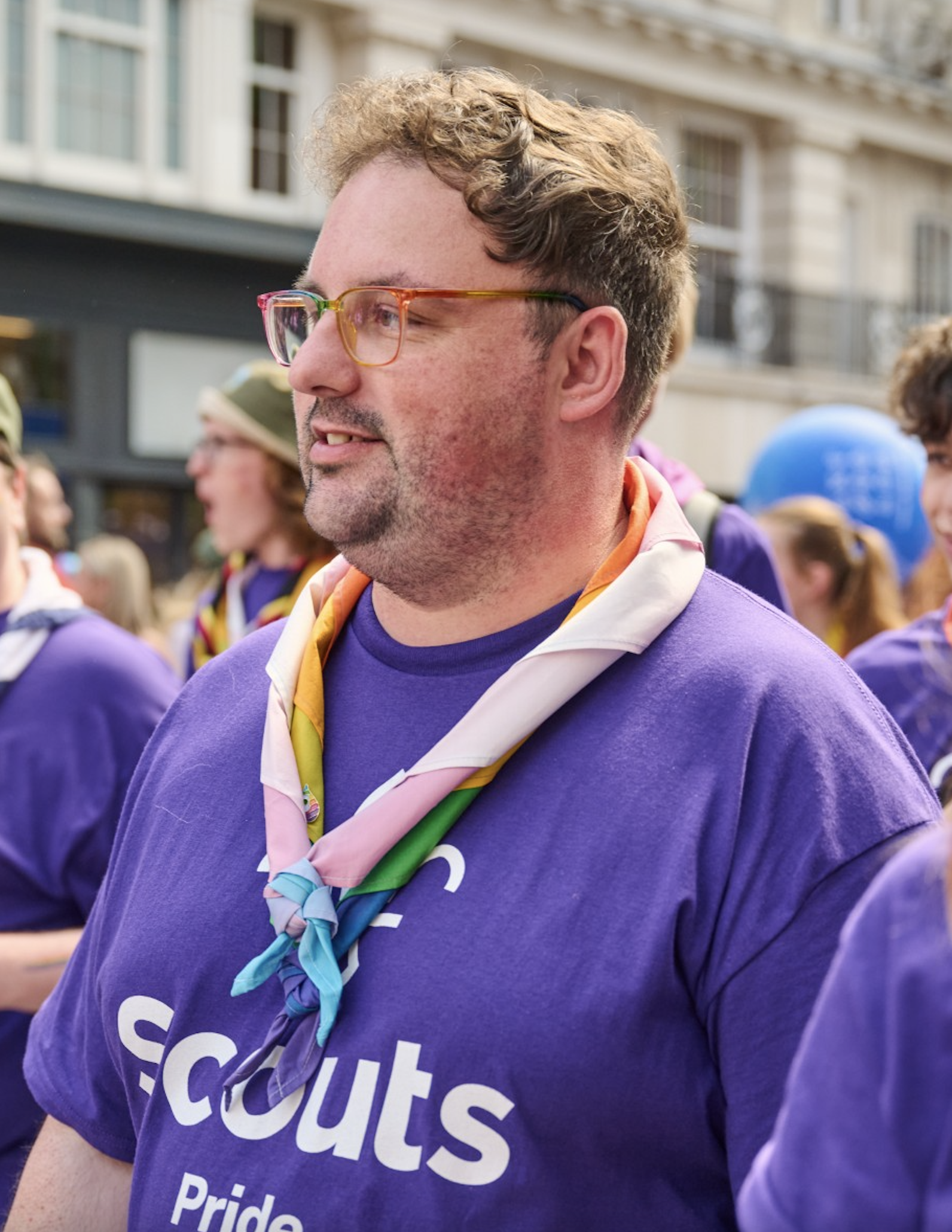 Marcus, wearing a purple Scouts t-shirt and rainbow necker, at London Pride.