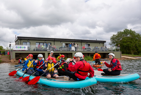 A group of young people pose for a picture while taking part in a water activity.