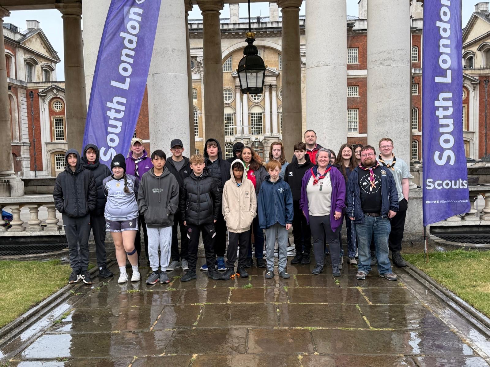 A group of Scouts pose for a picture outside a building.