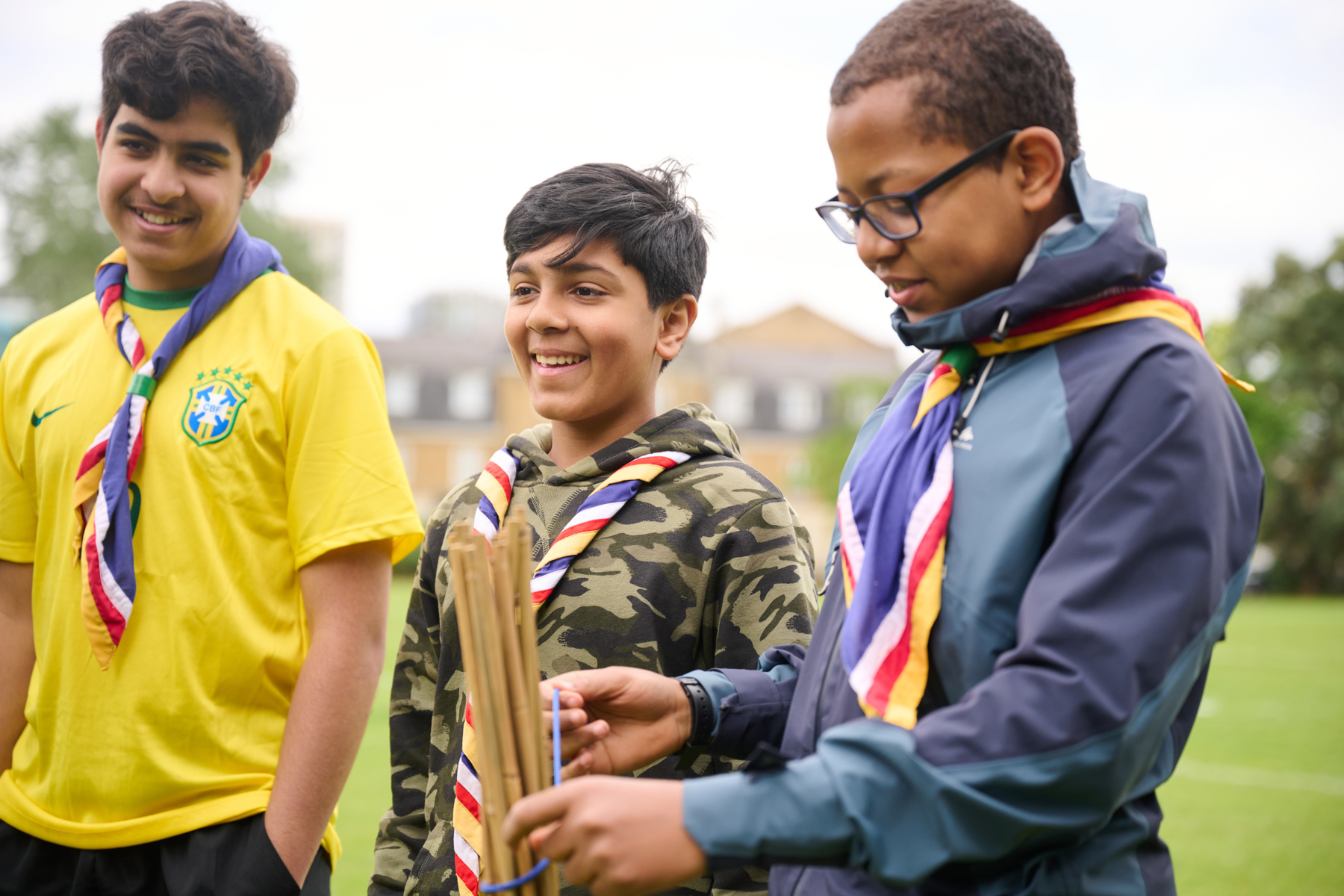 Three young people stand in a field smiling