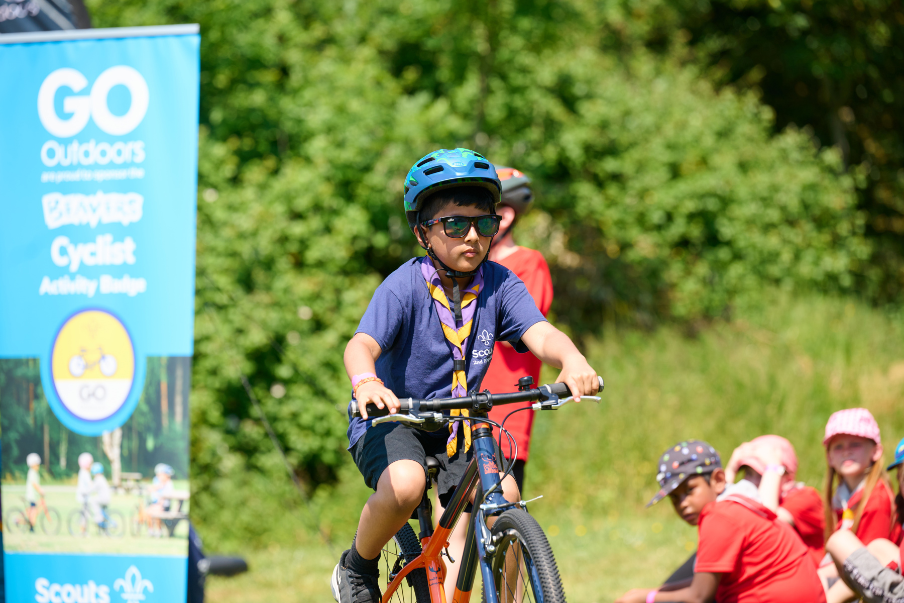 Beaver in a helmet and sunglasses cycles in a field