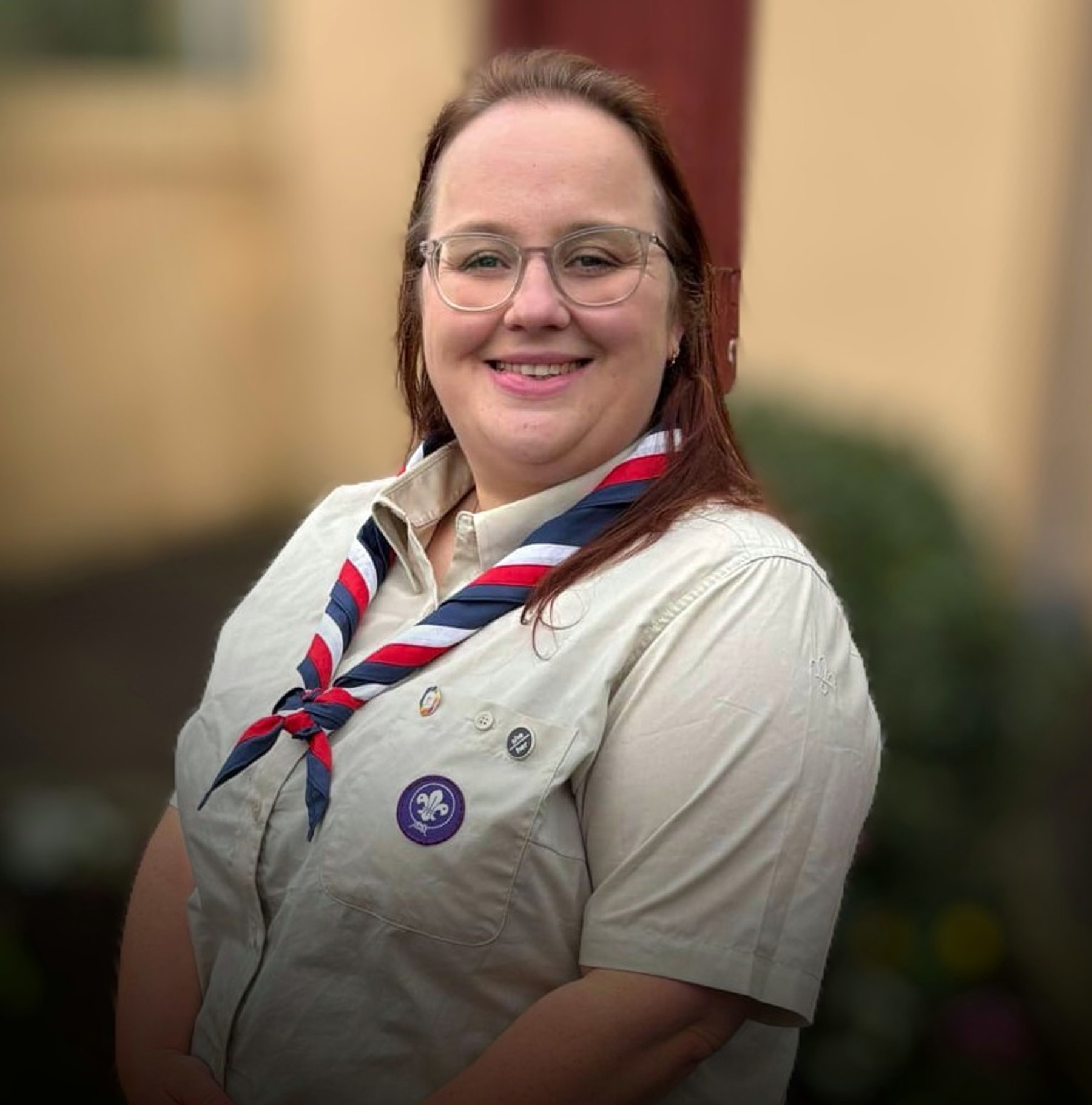 Rebecca is smiling and wearing an adult Scouts uniform and a red, white and blue necker.