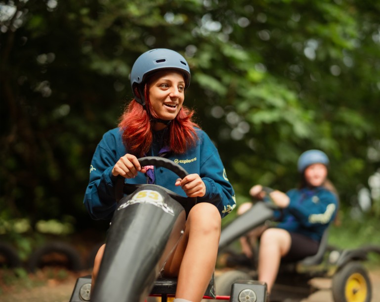 An Explorer wearing a helmet smiles while karting.