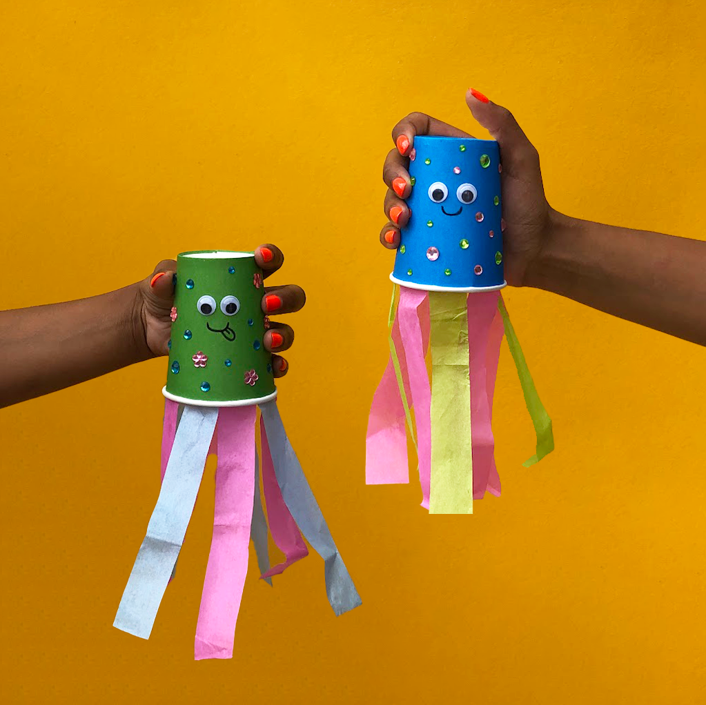 Two paper cup breathing buddies. The cups have tissue paper tassels from one end.