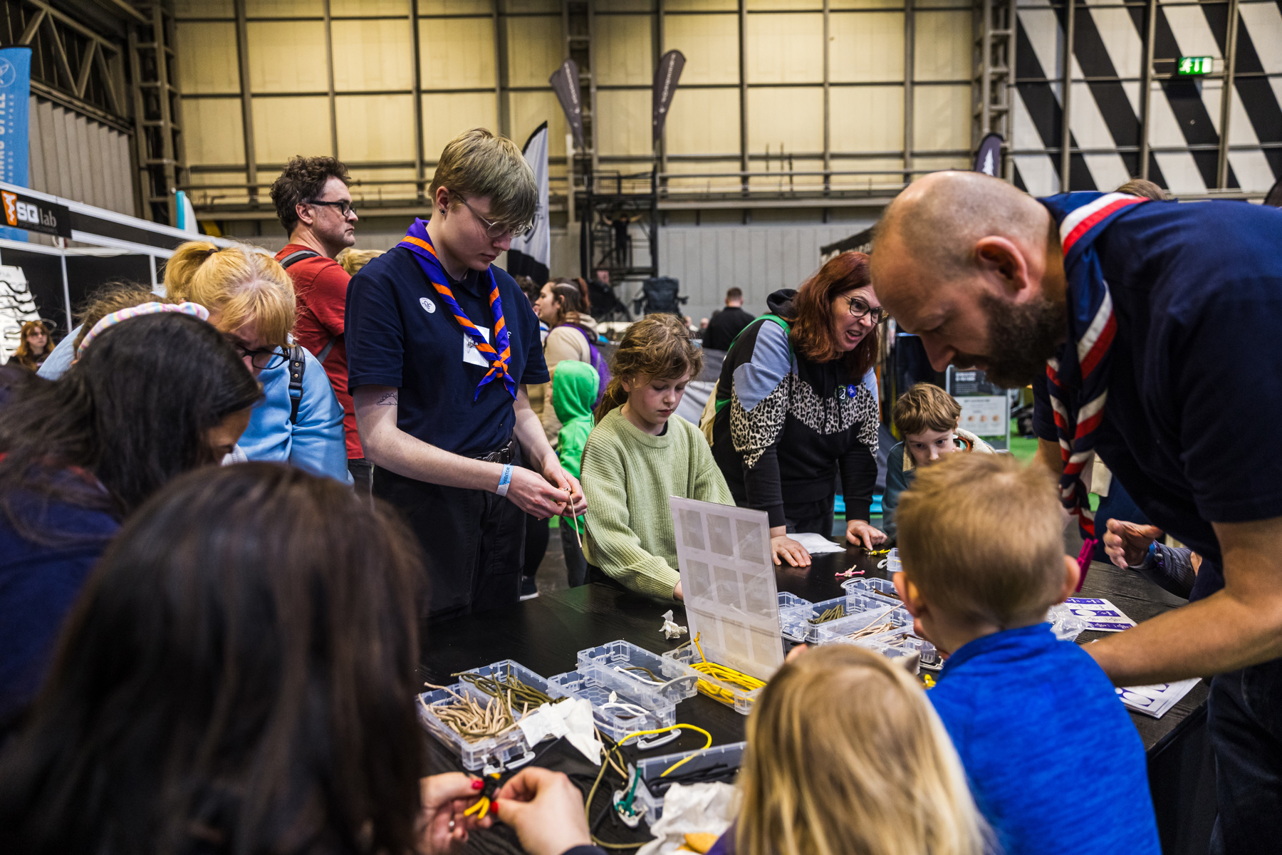 Scouts and young people standing around a table making paracord crafts at The National Outdoor Expo