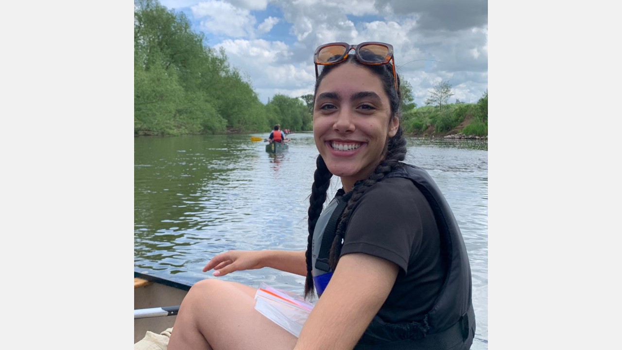 A young person smiling and sitting in a canoe
