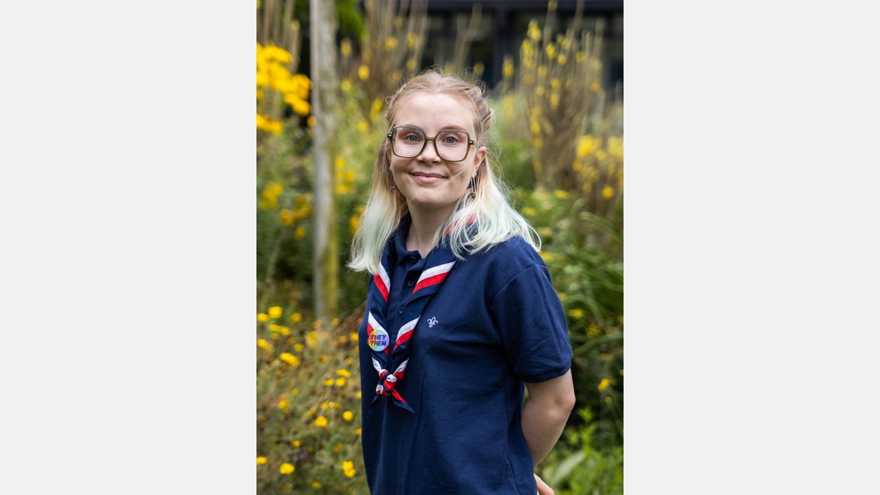 A young person wearing glasses, a Scouts polo and a UK necker