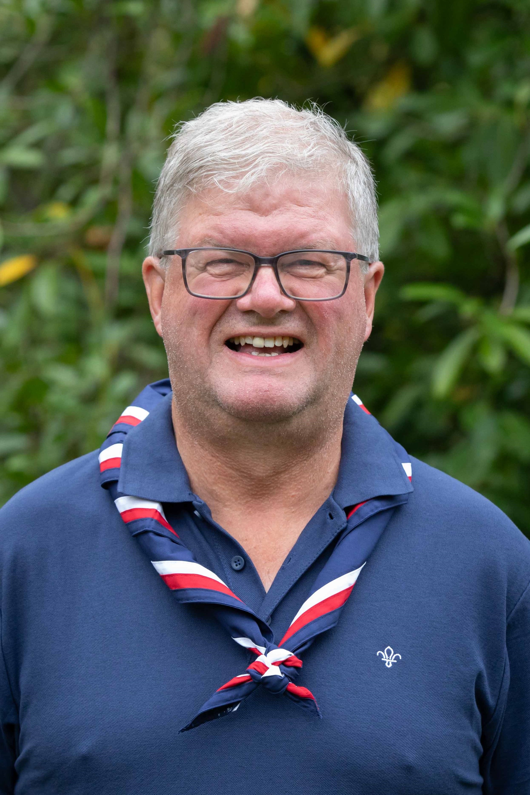 Callum, wearing a navy polo and red, white and blue necker, smiles at the camera.