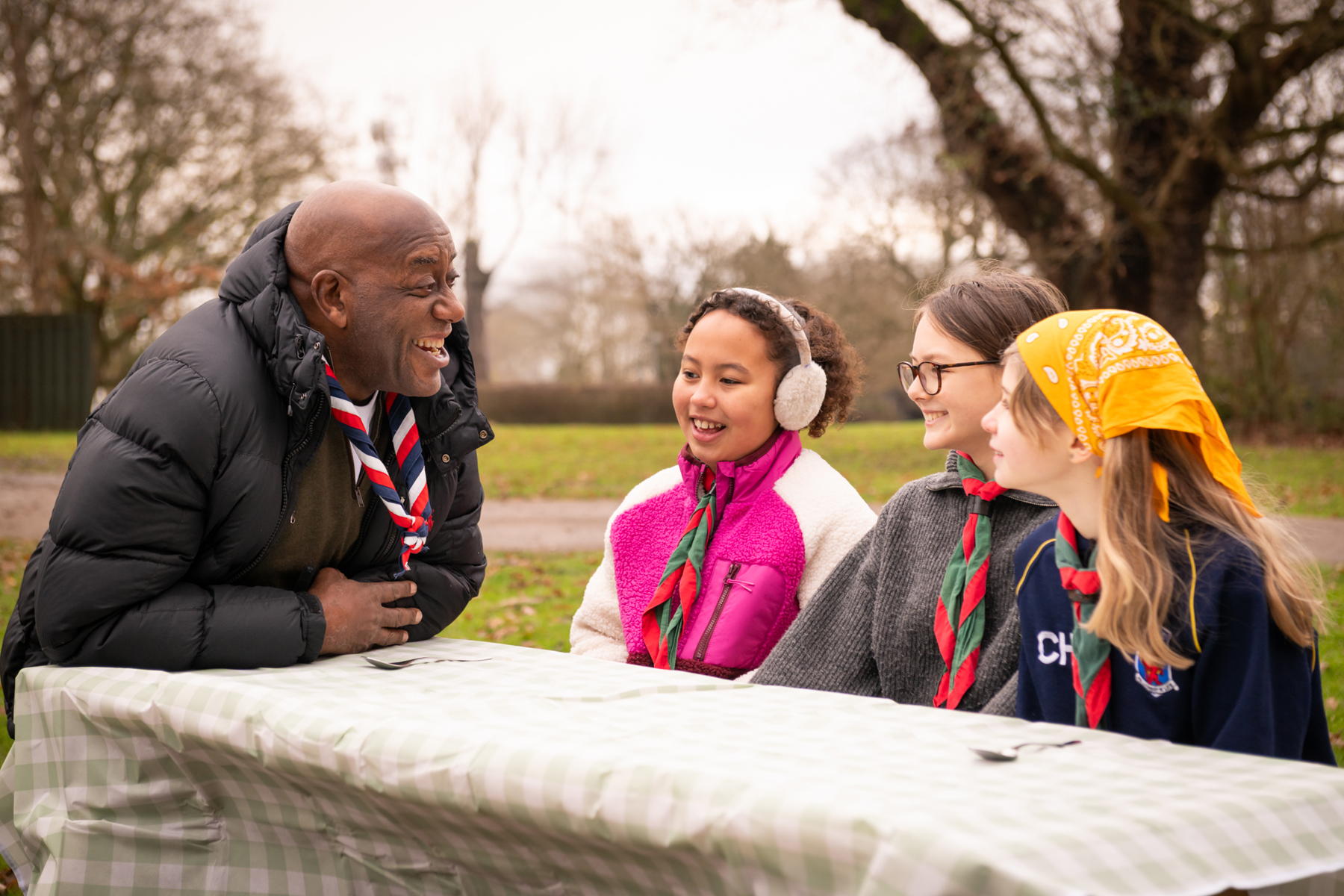 Ainsley Harriott smiles while talking to three Scouts.