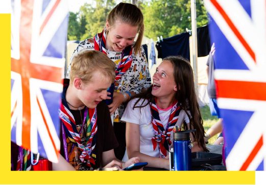 Three young people smile together with Union Jack flags in front of them