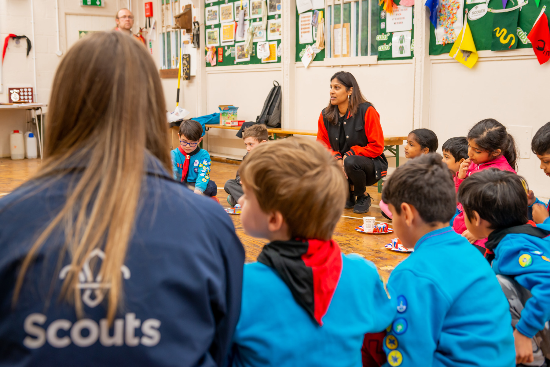 A group of Beavers in uniform sitting on the floor with HSBC Money Skills volunteers.